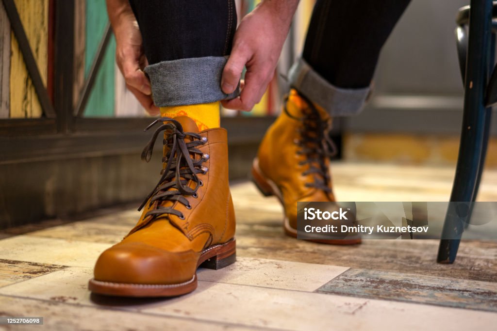 Man ordering his jeans and wearing yelloe brown brogues boots indoor, close up view Men old fashion boots close up view Boot Stock Photo
