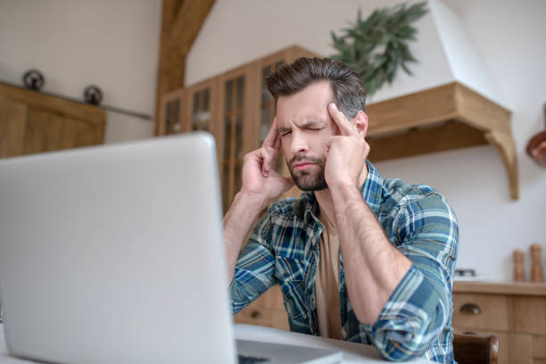 istock Man in a checkered shirt looking tired and suffering from headache 1252707617