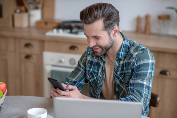 istock Man in a checkered shirt texting and smiling 1252707630