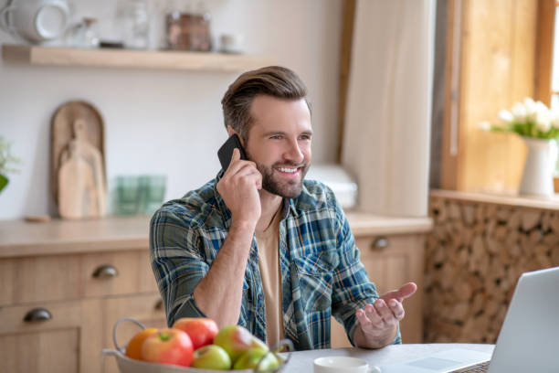 istock Man in a checkered shirt talking on the phone and looking contented 1252707635