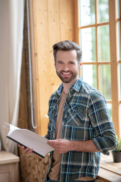 istock Man in a checkered shirt standing in the kitchen holding documents 1252707651