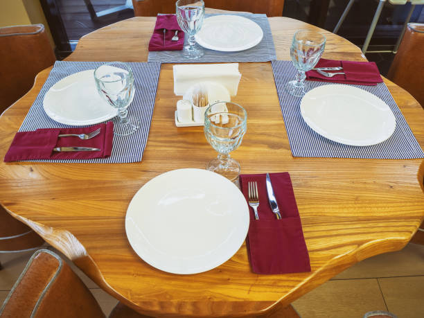 istock Carved round table with crystal glasses, plates, napkins and silverware. Table setting in a cafe 1252708738