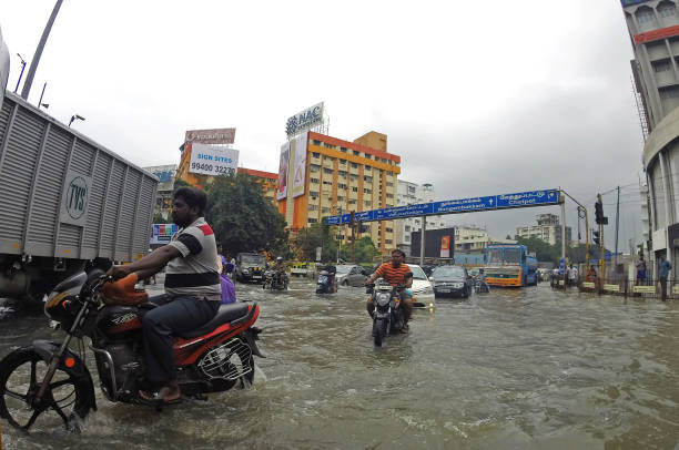 Traffic drive through a flooded intersection in Chennai, India Chennai, India - 3 December 2015: Motor bikes and vehicle traffic drive through a flooded intersection in Channai, India. chennai photos stock pictures, royalty-free photos & images