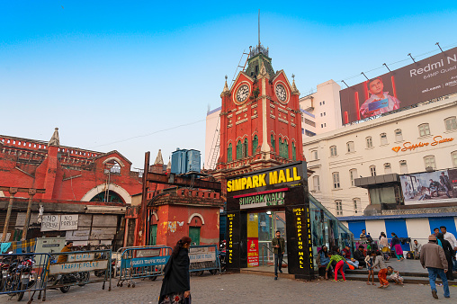 Kolkata, West Bengal, India - 29th December 2019 : Entrance of modern shopping Mall with Historic clock tower of New Market, in the background. Modern and vintage Kolkata city in a single frame.