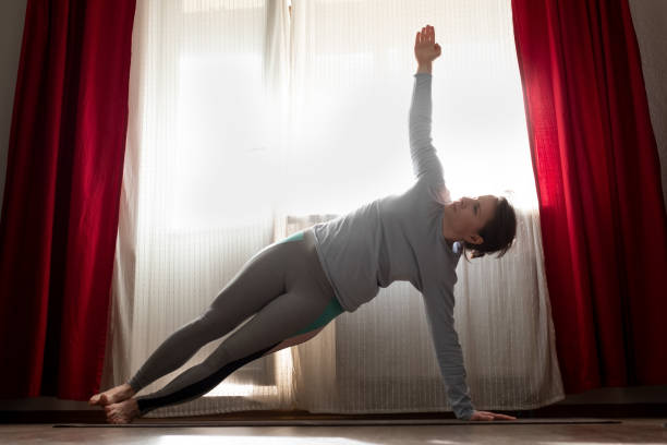istock young woman doing side plank pose at home. 1252714431