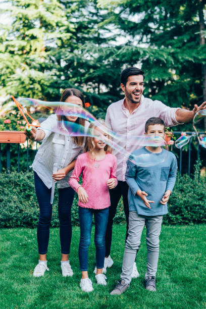 famille ayant l’amusement dans l’arrière-cour avec des bulles de savon. - bubble wand outdoors little boys mother photos et images de collection