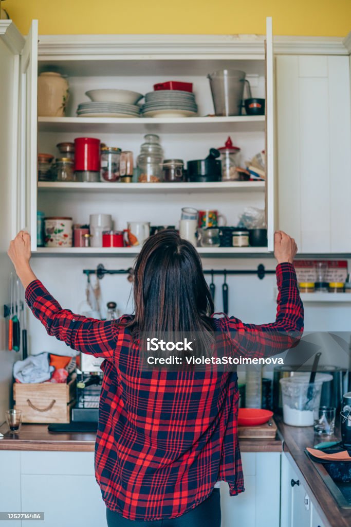 Housewife organizing the kitchen. Rear view of a young woman organizing her kitchen at home. Kitchen Stock Photo