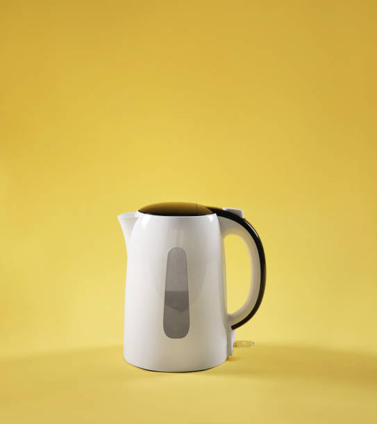 White electric kettle on table on yellow background