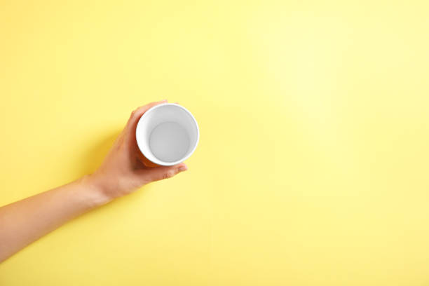 istock Disposable glass in hand on yellow background, top wiew 1252716610