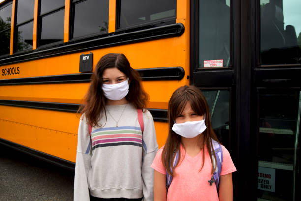 istock Two children wearing face masks by school bus 1252718686