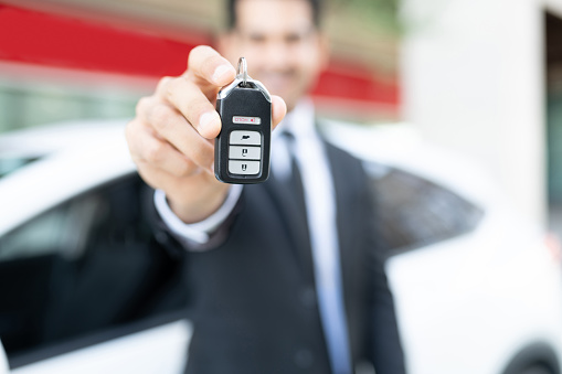 Young Hispanic male dealer showing car key