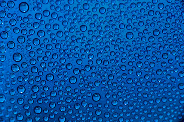 Small blue water drops of condensation on clear surface