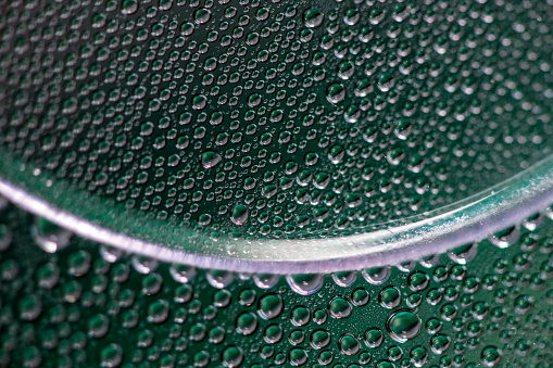 Macro water droplets on a curved surface green and silver colour cast