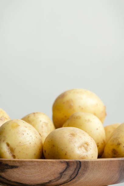 Young potato in a wooden bowl. Monochrome image with copy space.