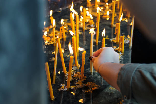 plan rapproché de la main de jeune femme allumant une bougie dans l’église - candle memorial vigil praying candlelight photos et images de collection