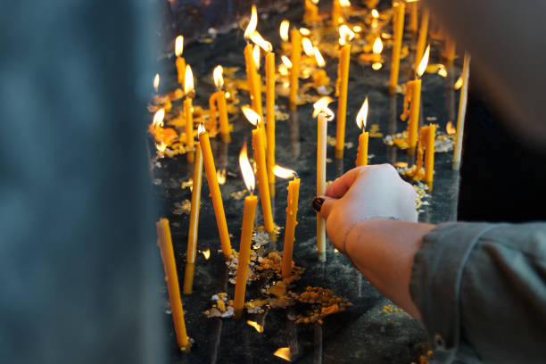 Close-Up Of Young Woman Hand Lighting A Candle In Church stock photo
