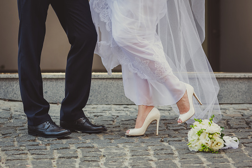Feet in footwear of the groom and the bride and flowers
