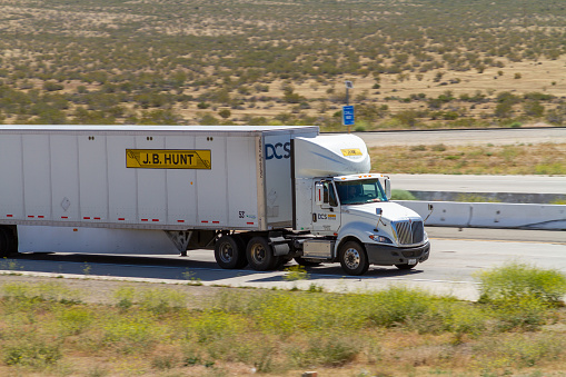 Apple Valley, CA / USA – May 16, 2020: White J.B. Hunt semi-truck on Interstate 15 in the Mojave Desert near the Town of Apple Valley, California.