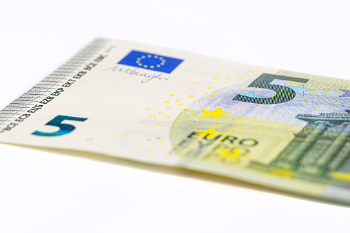 Macro shot of a European Union banknote of 5 EUR, close-up of the number five, isolated on a white background, selective focus.