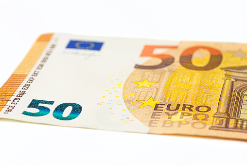 Macro shot of a European Union banknote of 50 EUR, close-up of the number fifty, isolated on a white background, selective focus.