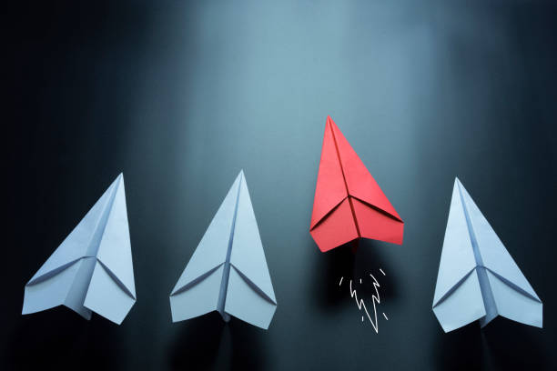 Leadership concept with red paper plane leading among white on black background