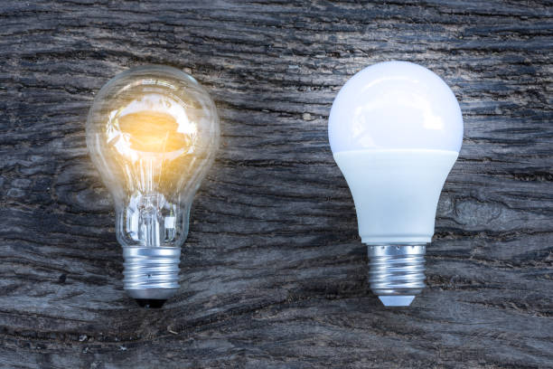 istock LED and Fluorescent bulb with light on on wooden background, Power energy saving concept. 1252736572