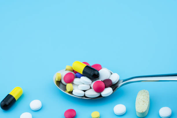 istock Assorted pharmaceutical medicine pills, tablets and capsules on spoon, blue background 1252736588