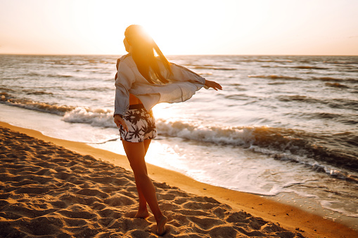 Girl enjoys vacation on the beach at sunset. The concept of relax, travel, freedom and summer vacation.