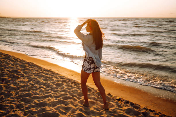 Girl enjoys vacation on the beach at sunset. The concept of relax, travel, freedom and summer vacation.