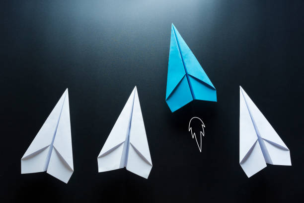 istock Leadership concept with blue paper plane leading among white on black background 1252736858