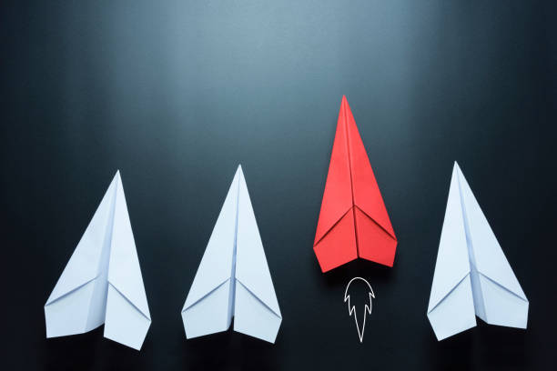 istock Leadership concept with red paper plane leading among white on black background 1252736930