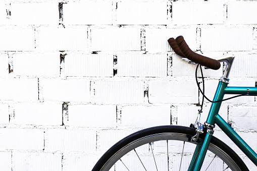 Isolated handlebar of an old bicycle on a white brick wall. Hipster style, horizontal photography.