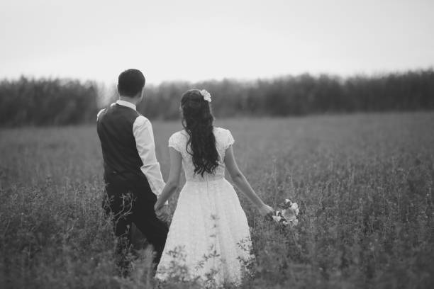 Bride and groom hold hands and meet the sunset. Wedding