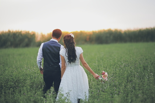Wedding. Bride and groom hold hands and meet the sunset. A beautiful couple. High quality photo