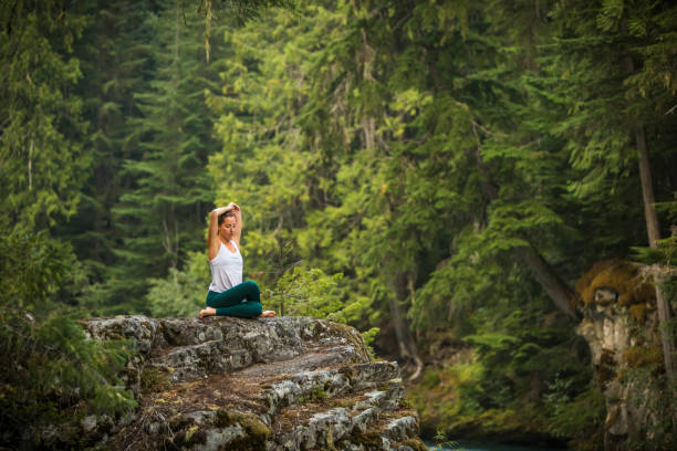 Young woman practicing yoga and meditation in forest setting. stock photo