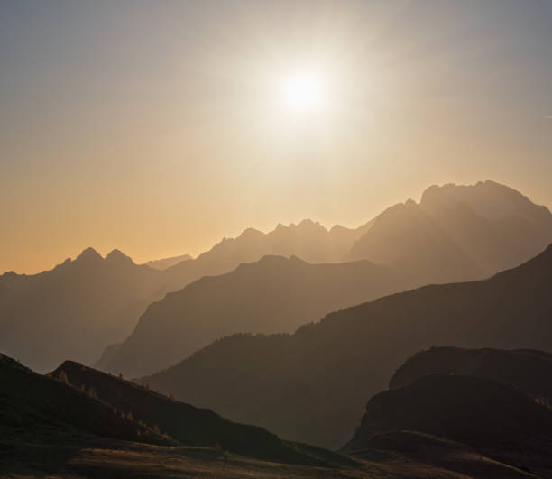 istock Sun glow in evening hazy sky and mountain silhouettes view 1252751965