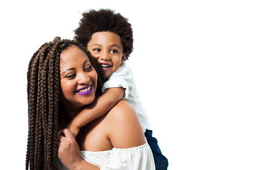 Black beautiful son hugging mom from behind both smiling - Studio shot