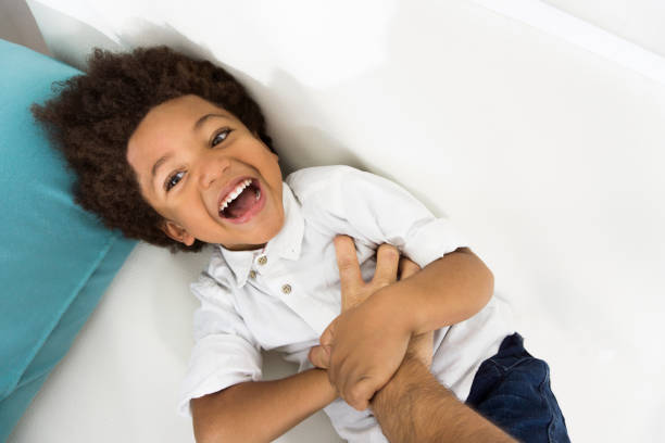 Funny boy with tongue out lying on white floor, wearing blue T-shirt. Isolated on white background image.