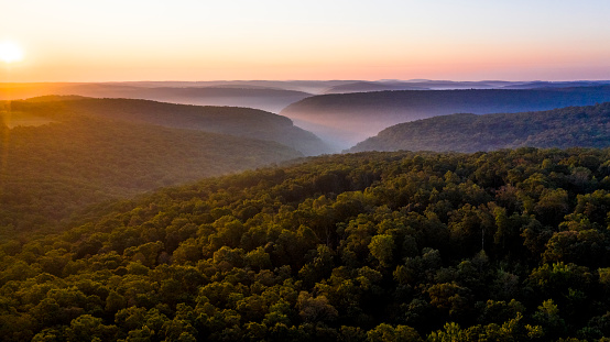 The sun rises over ridges with valley fog in the remote Ozark Mountains.