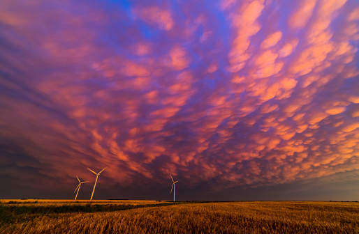 Sunset colors reflecting off mammatus clouds in western Kansas with wind turbines on the horizon.