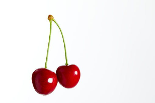 Two red cherries on white background