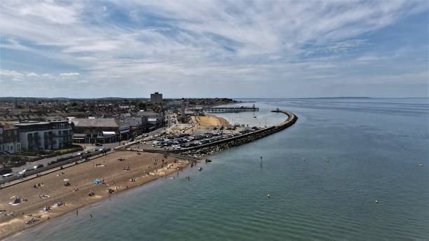 Neptunes Arm, Herne Bay, Looking North Shot of Herne Bay's coast at the neptunes arm, car park and walkway and clock tower in middle distance. herne bay photos stock pictures, royalty-free photos & images