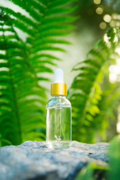 Natural Serums in glass bottle On stone with Ferns leaves in forest summer day. Aromatherapy oil, concept of natural cosmetic Natural Serums in glass bottle On stone with Ferns leaves in forest summer day. Aromatherapy oil, concept of natural cosmetic face serum photos stock pictures, royalty-free photos & images