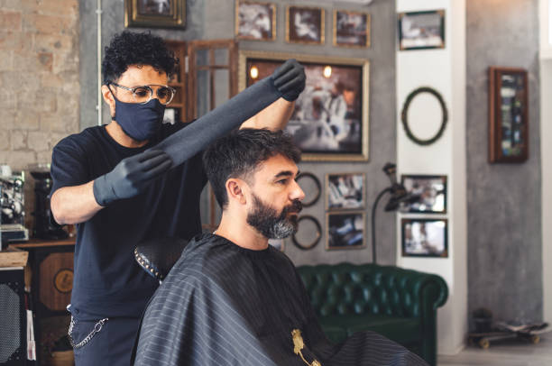 istock Barber preparing neck cover paper in a client with cape 1252761974