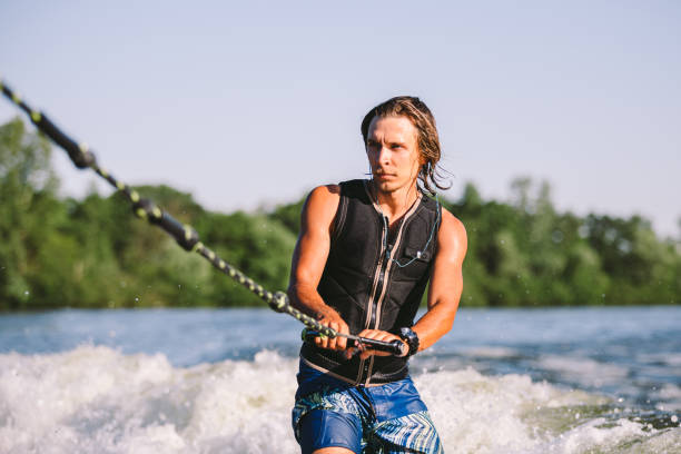 istock Active wakesurfer jumping on wake board down the river waves. Surfer on wave. Male athlete training on wakesurf training. Active water sports in open air on board. A man catches a wave on surf 1252770965