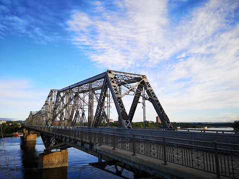 Ottawa, Canada - June 1, 2020: The Alexandra Bridge stretches from downtown Ottawa to downtown Gatineau over the Ottawa River.  It is a steel truss cantilever bridge with five spans which opened in 1901.  There is  dedicated pedestrian and bicycle section.