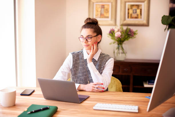 istock Thinking woman using laptop while sitting at desk at home daydreaming 1252775278