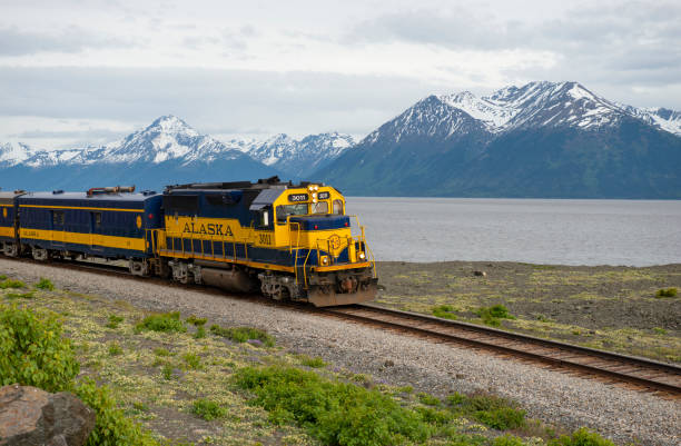 Train route along water with mountains in the background between Anchorge and Girdwood, Alaska.
