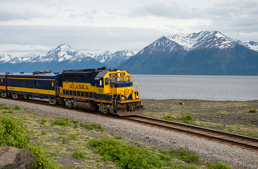 Train route along water with mountains in the background between Anchorge and Girdwood, Alaska.