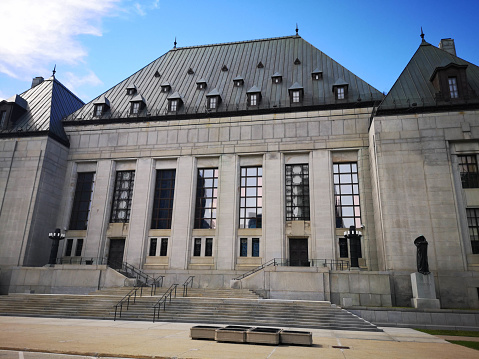 Ottawa, Canada - June 6, 2020: The Supreme Court of Canada is situated in downtown Ottawa.  It is Canada's highest court and issues decisions on a wide range of issues from the status of Uber drivers to the right of Canadians to have medical assistance in dying.  Construction began in 1939 in an Art Deco style.  Statues of Truth and Justice flank the central stairwell.